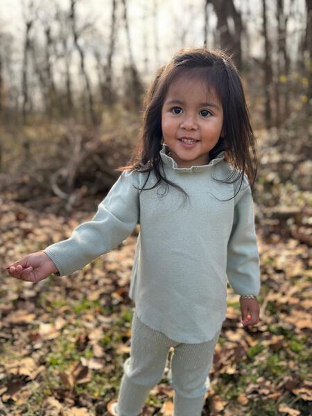 happy girl in autumn wood wearing green cotton knit sweater with ruffle neck and matching leggings