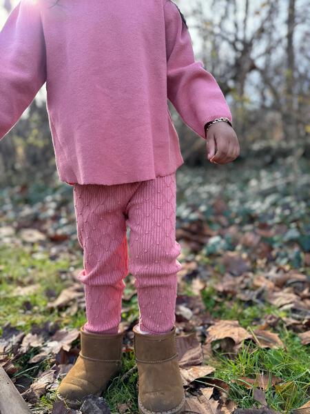 girl in autumnal wood wearing pink patterned knit leggings and matching  knitted sweater