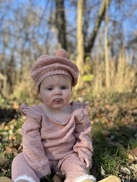 baby in winter woods wearing pink cotton knit pompom beret hat and matching romper