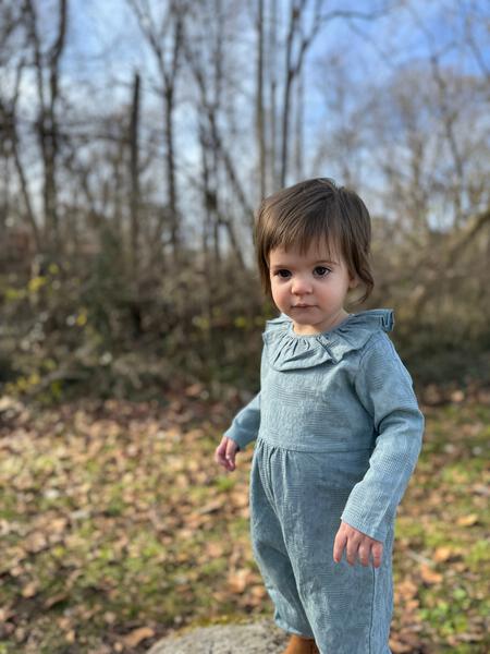 toddler in autumn wood wearing long sleeved blue romper with ruffle collar