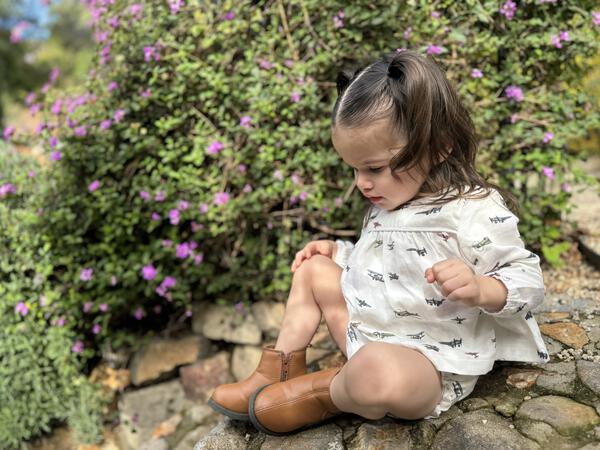 toddler in garden in sunshine wearing white short dress with matching bloomers in all over airplane print