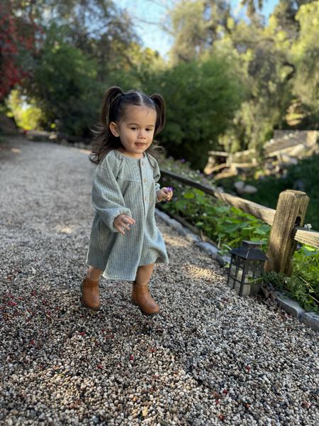 toddler running in sunny autumn garden wearing green long sleeved jersey rib dress. buttons down the front