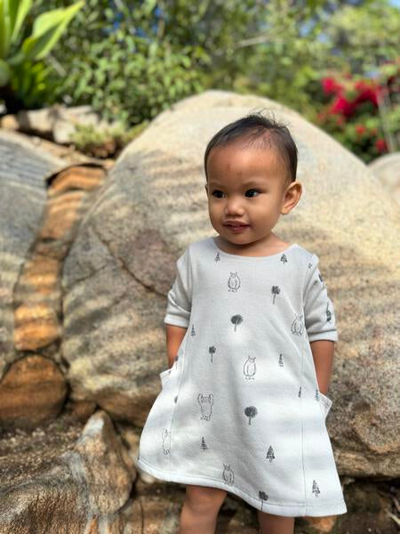 happy toddler with hands in pockets wearing grey yeti print dress with 3/4 length sleeves a-line with side patch pockets