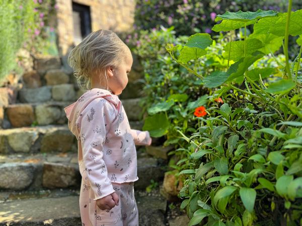 toddler in autumn sunshine wearing pink hooded sweat top with patch pocket and all over flower print and matching sweat pants with side patch pockets