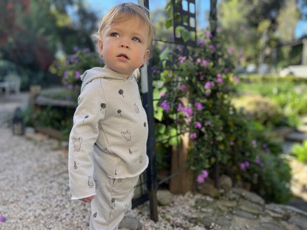 toddler in autumn sunshine wearing grey hooded sweat top with patch pocket and all over yeti print and matching sweat pants