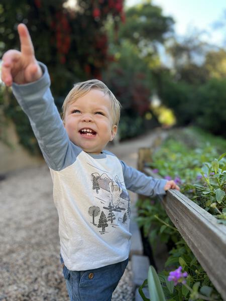 toddler in garden wearing raglan style long sleeve tee with yeti print