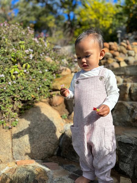 happy toddler in autumn sunshine wearing pink jersey rib overalls with side patch pockets