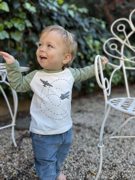 happy toddler in garden wearing raglan style long sleeve tee with airplane print