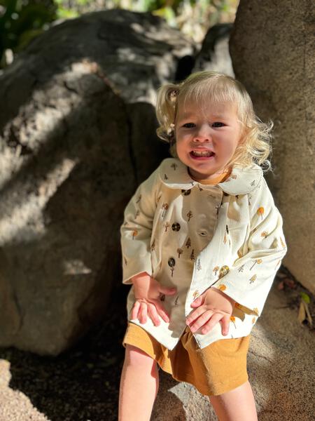 toddler in sunshine wearing cord jacket with double breasted buttons and peter pan collar cream tree print