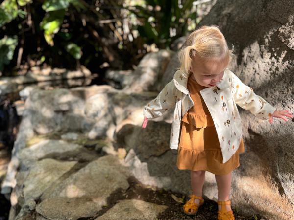 toddler in sunshine wearing cord jacket with double breasted buttons and peter pan collar cream tree print