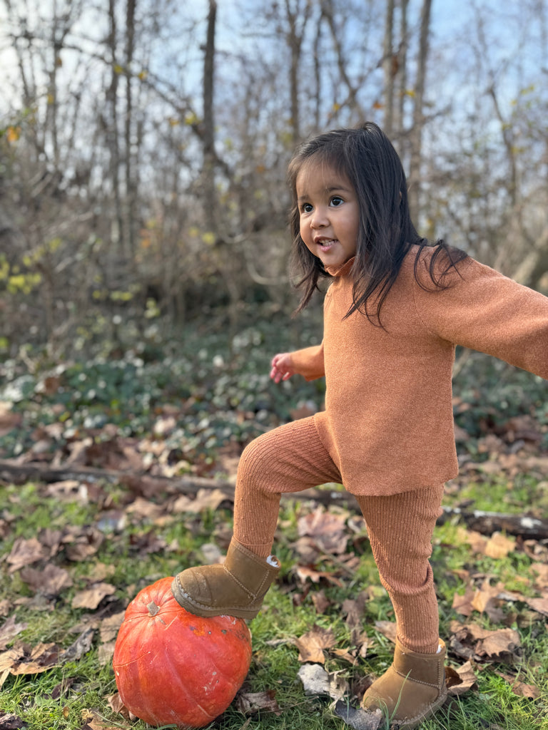 girl in autumnal wood wearing gold patterned knit leggings and matching  knitted sweater