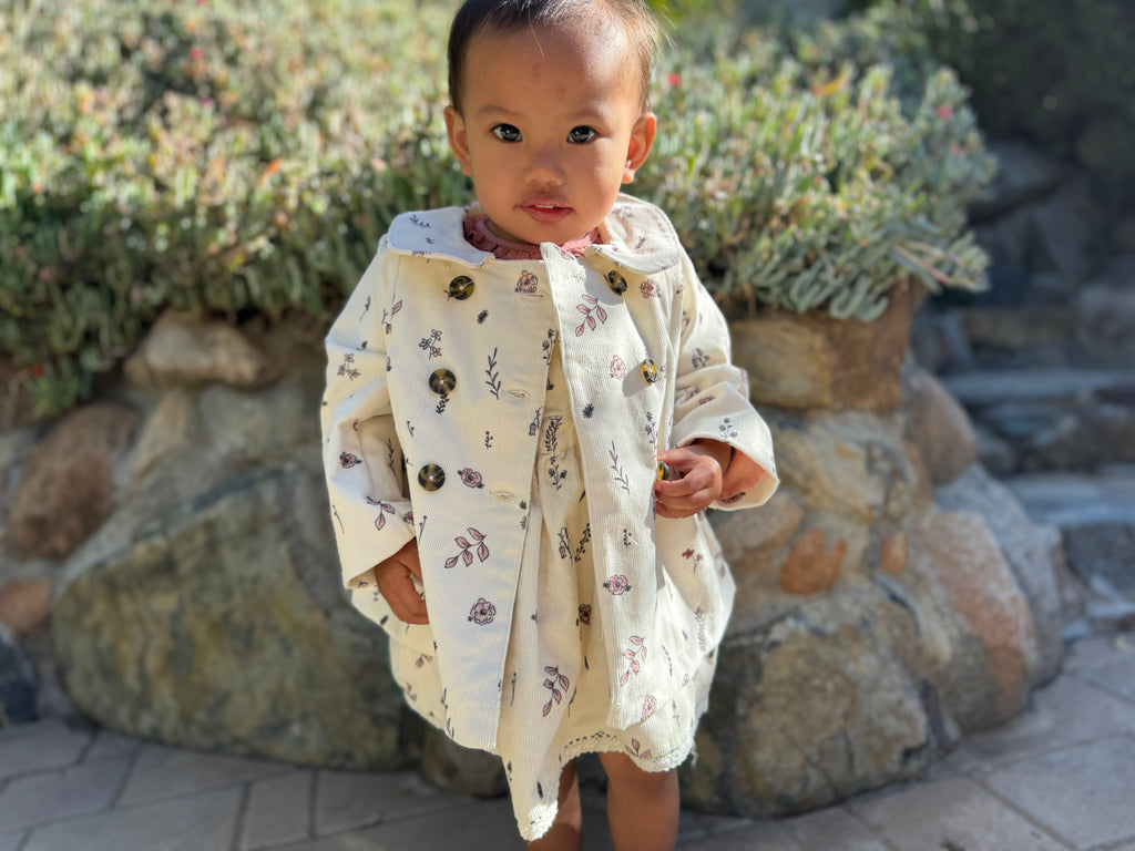 toddler in sunshine wearing cord jacket with double breasted buttons and peter pan collar cream floral print